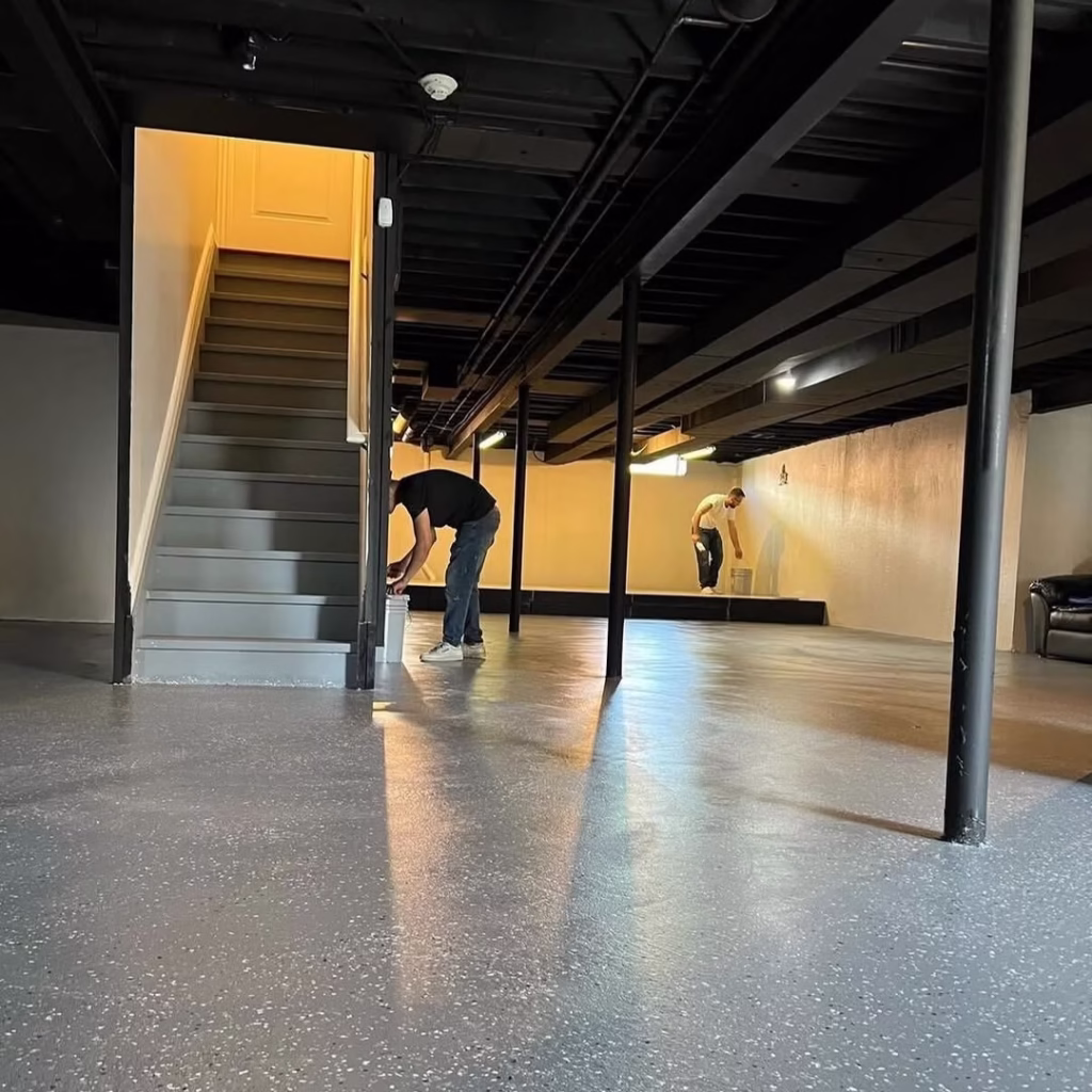Basement with black painted exposed ceiling and staircase