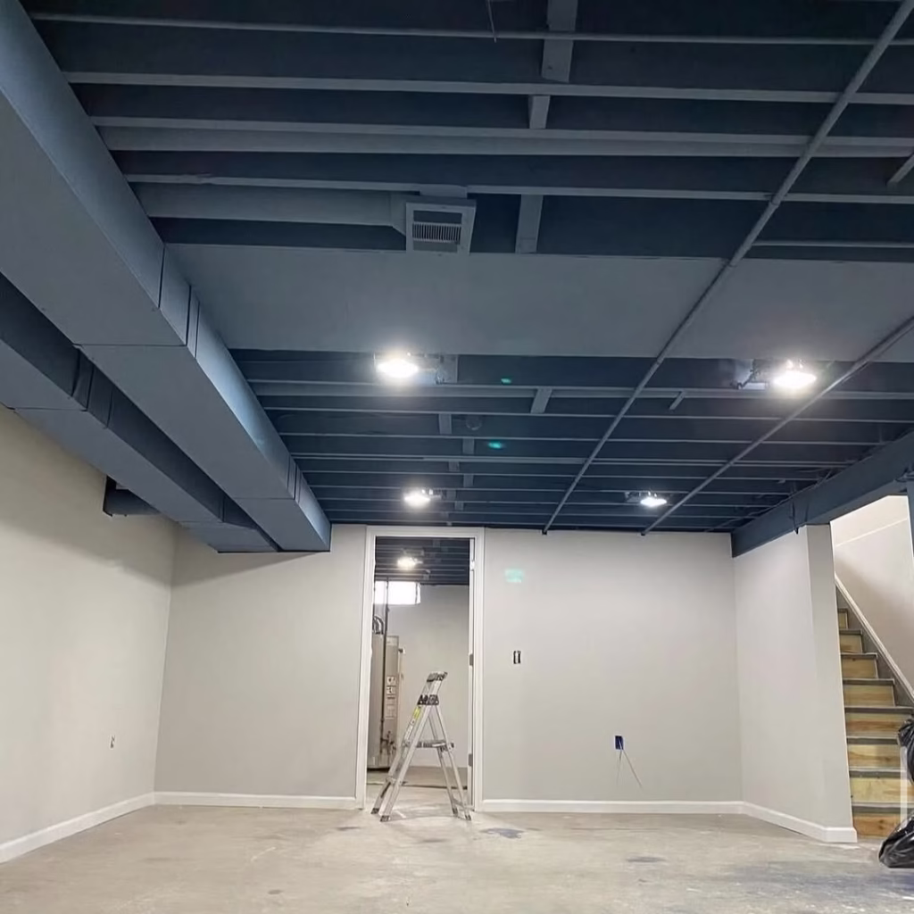 Basement with dark painted exposed ceiling and recessed lights