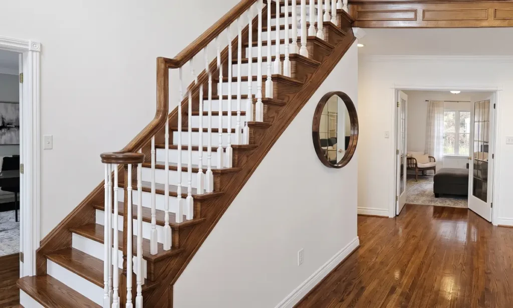 Staircase with white balusters and a wood handrail in a freshly painted entry