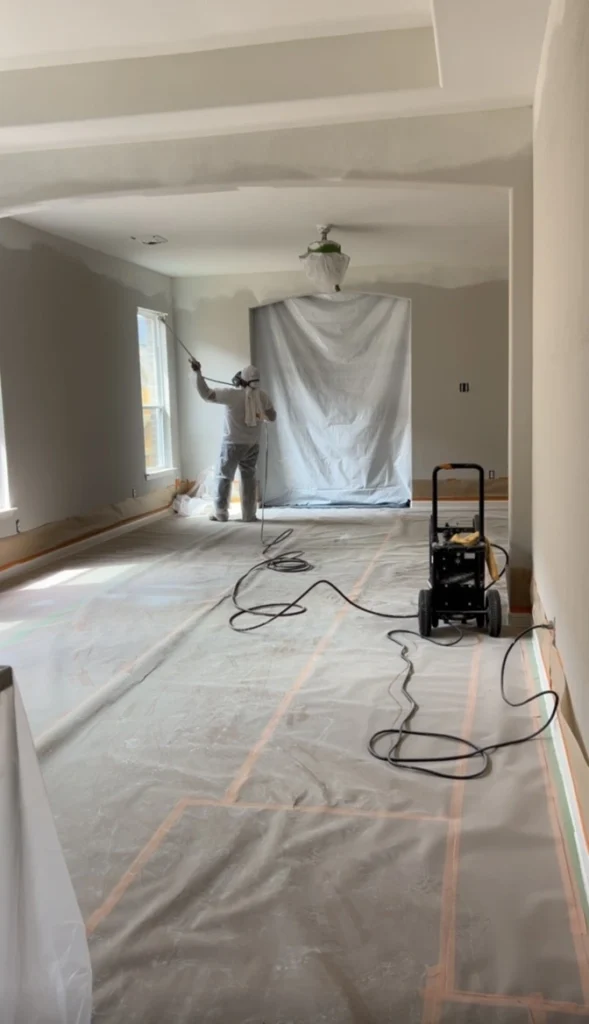 Room covered in plastic sheeting and drop cloths before interior painting
