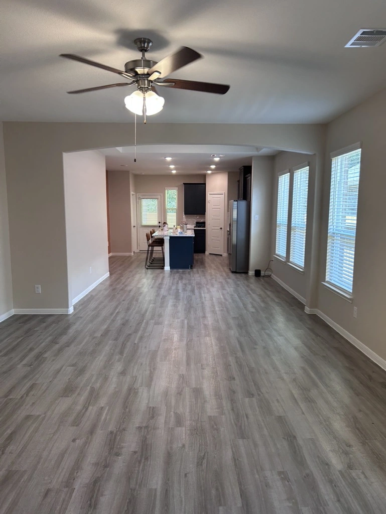 Open living area with light gray walls and wood-look floors after painting