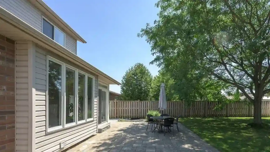 Back of a house with gray siding and a stone patio