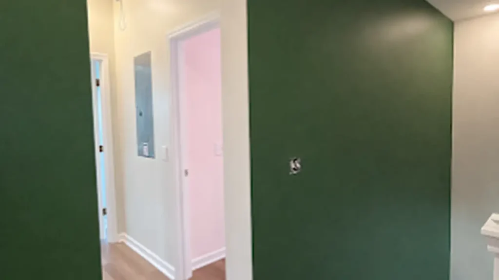 Hallway with a dark green accent wall and white doors