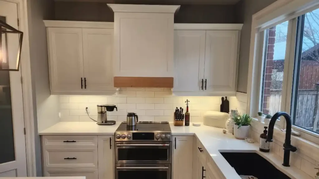 Kitchen with white painted cabinets and a wood range hood